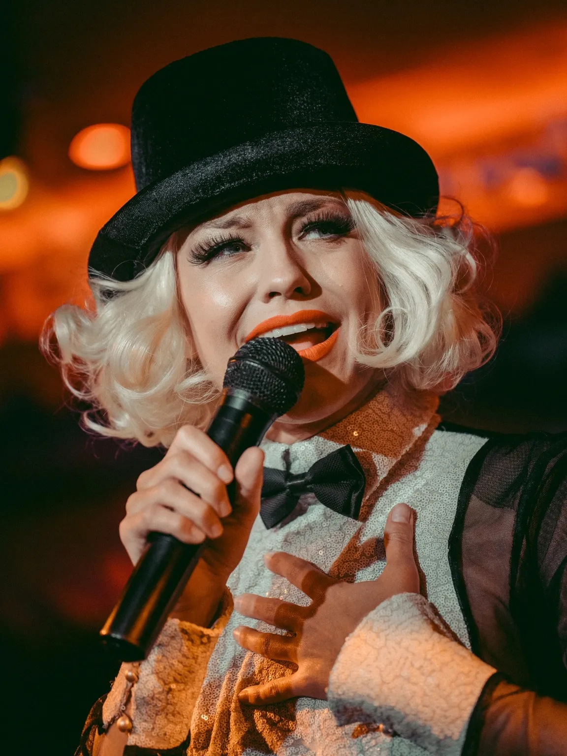 A singer in a top hat mid-song at Coup de Foudre